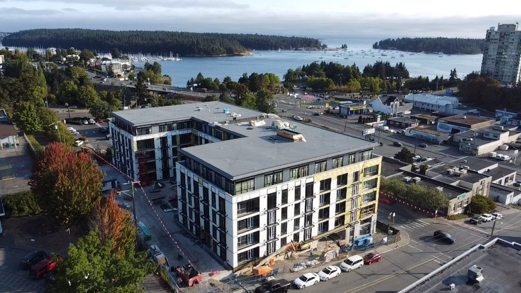 Drone photo of the 340 Campbell Street mixed-use development in downtown Nanaimo, showing exterior siding nearing completion and its proximity to the waterfront.