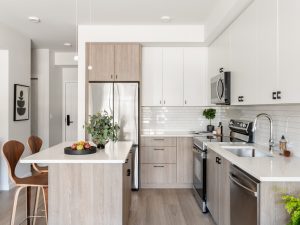 Modern apartment kitchen at Link on Long Lake in Nanaimo, featuring an island, stainless steel appliances and contemporary finishes.