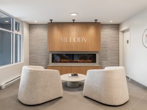 Lobby seating area at Melody multi-family rental development in Nanaimo, featuring a fireplace and contemporary wood finishes.
